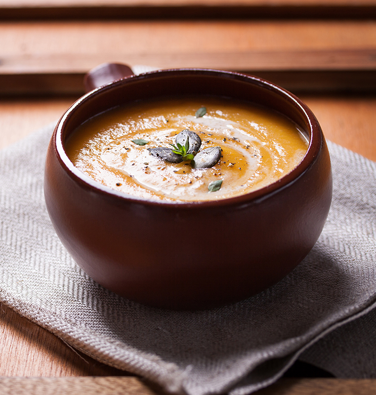 Homemade tasty creamy pumpkin soup puree in a bowl on a wooden background